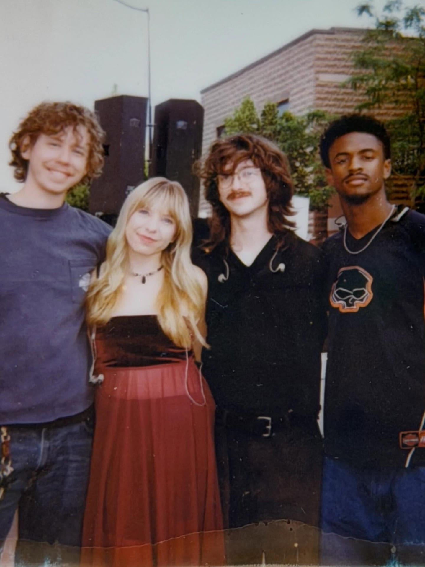 Tiffany Johnson standing outdoors with the three musicians in her band