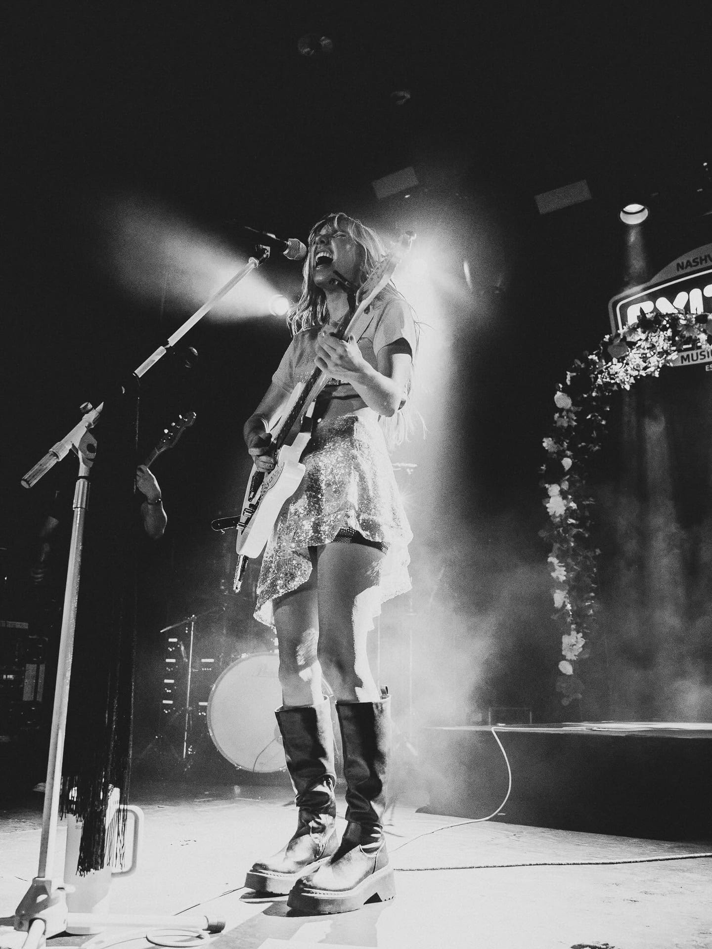 Black-and-white photograph of Tiffany Johnson singing into a microphone on a smoky stage